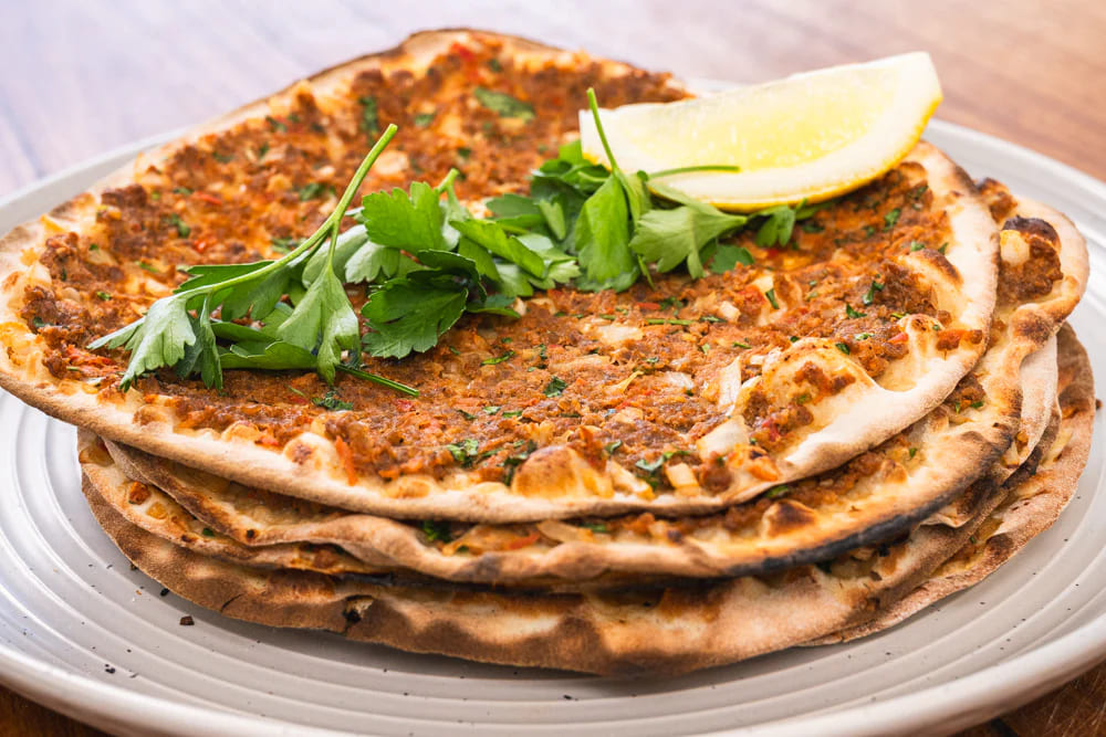 ẩm thực thổ nhĩ kỳ Lahmacun là món bánh pizza Thổ Nhĩ Kỳ, phủ thịt băm và rau củ, thơm ngon đậm vị